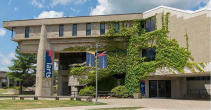 Cement three story building with ivy growing up the front and banner with the word larts hanging from it