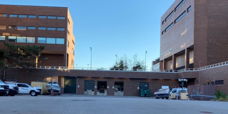 Photo of two four story brick buildings attached by a one level loading dock with multiple bays between the two taller structures