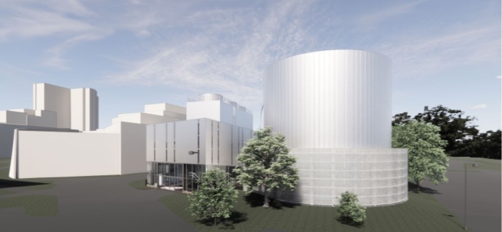 A multi level and section building, white, with some trees around it, in the forefront of the photo is a round cylinder structure