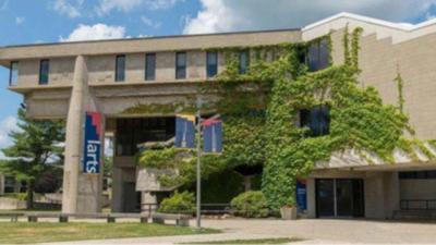 Cement three story building with ivy growing up the front and banner with the word larts hanging from it