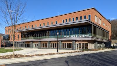 Three story mixed material building. Worcester Commons is on the front of the building in silver metal block letters.