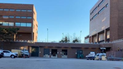 Photo of two four story brick buildings attached by a one level loading dock with multiple bays between the two taller structures
